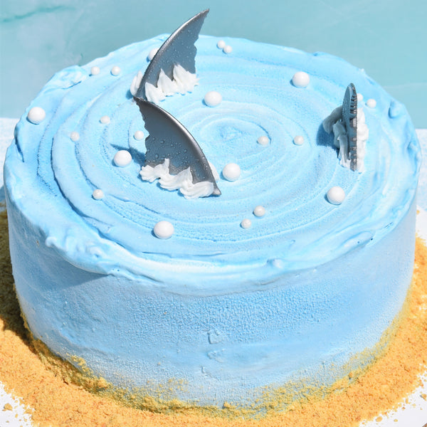 Blue cake with shark fins on a sandy base